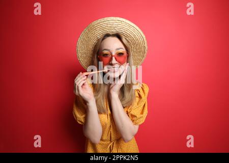 Jeune femme à la mode mâchant du bubblegum sur fond rouge Banque D'Images