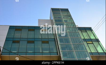 Immeuble de bureaux modernes avec des murs transparents en verre contre le ciel bleu Banque D'Images