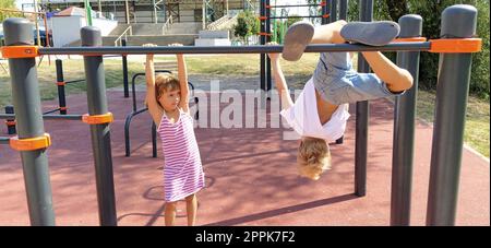 Sremska Mitrovica, Serbie, 13 septembre 2020. Un garçon et une fille sur le sport ou le terrain de jeu sont engagés dans l'exercice physique. Enfant dans un t-shirt blanc. Fille dans une robe rayée rit. Banque D'Images