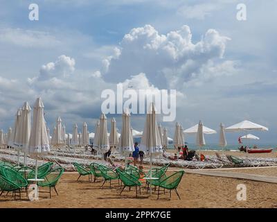 Anapa, Russie, 15 août 2021 chaises longues et parasols sur la plage de sable après la pluie. Saison de plage. Café de plage avec chaises en osier. Touristes marchant les gens. Un avertissement de tempête. Nuages de Cumulus Banque D'Images