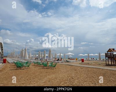 Anapa, Russie, 15 août 2021 chaises longues et parasols sur la plage de sable après la pluie. Saison de plage. Café de plage avec chaises en osier. Touristes marchant les gens. Un avertissement de tempête. Nuages de Cumulus Banque D'Images