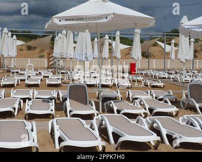 Anapa, Russie, le 15 août 2021 transats humides et parasols sur la plage de la mer pendant une forte pluie. Parasol roulé sur la plage contre le ciel nuageux sombre. Invasion d'un typhon, d'un cyclone ou d'une tempête Banque D'Images