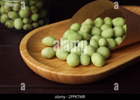 Cacahuètes savoureuses recouvertes de wasabi sur table en bois, en gros plan Banque D'Images