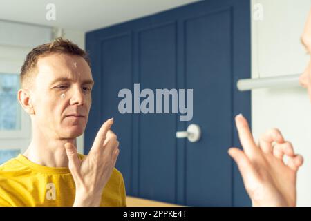 Homme mature appliquer la crème hydratante avec le doigt sur les zones claires du visage. Portrait masculin dans le miroir de la chambre. Concept de soin de la peau. Banque D'Images