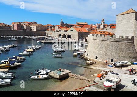 Dubrovnik, Croatie, 14 août 2022. Port de ville en été, attraction touristique. Les touristes marchent, montent dans les bateaux et les bateaux et font des excursions en bateau. Mer Adriatique. Un résident local joue avec un chien. Vieux forts. Banque D'Images