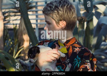 Gros plan belle femme tenant un petit chiot en portrait de jardin Banque D'Images