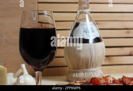 Pizza fraîche sur une table en bois au restaurant avec une bouteille de Chianti en arrière-plan Banque D'Images