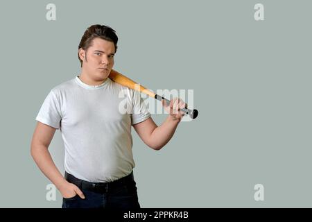 Un homme élégant tient une batte sur son épaule sur un fond gris isolé Banque D'Images