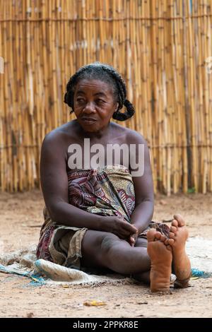 Femme malgache aînée se détendant en face de la cabane, il n'y a pas d'opportunité d'emploi ici. La vie quotidienne dans la campagne de Madagascar. Banque D'Images