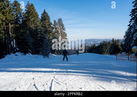 Piste de ski sur la Wasserkuppe avec skieurs et canon à neige sur le côté Banque D'Images