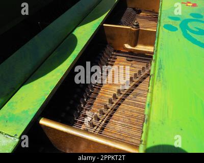 Cordes, table d'harmonie et mécanique de piano. Piano dans la rue. Piano peint en vert. Exécution d'un morceau de musique. Concert de rue par une journée ensoleillée d'été. Banque D'Images