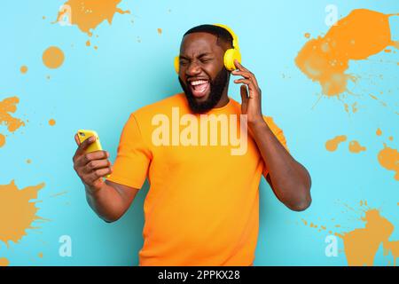 Garçon avec casque jaune écoute de la musique et des danses et énergique expression émotionnelle. Banque D'Images