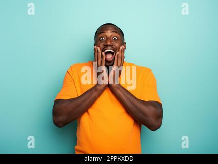 Surpris et choqué expression d'un garçon sur fond cyan Banque D'Images