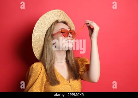 Jeune femme à la mode mâchant du bubblegum sur fond rouge Banque D'Images