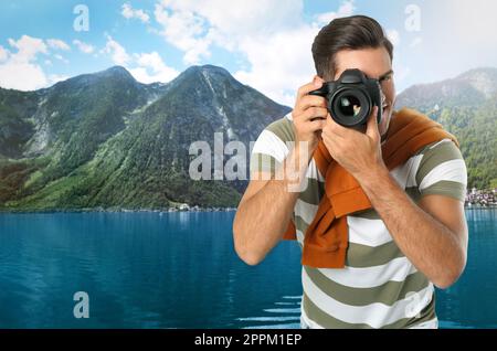 Photographe tenant un appareil photo professionnel et vue pittoresque sur les montagnes et la rivière en arrière-plan, espace pour le texte Banque D'Images