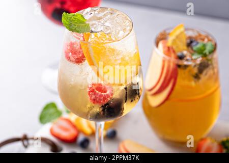 Des sangrias rafraîchissants aux baies d'été avec du vin blanc et rouge, des pommes et des oranges, une variété de boissons Banque D'Images