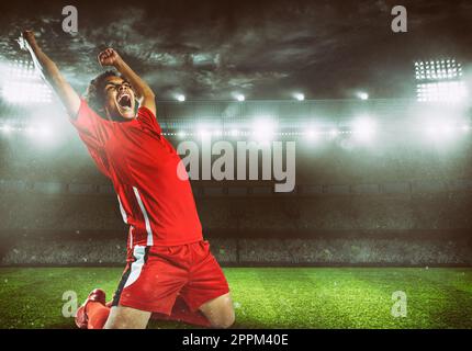 L'attaquant en uniforme rouge se réjouit de la victoire au stade Banque D'Images