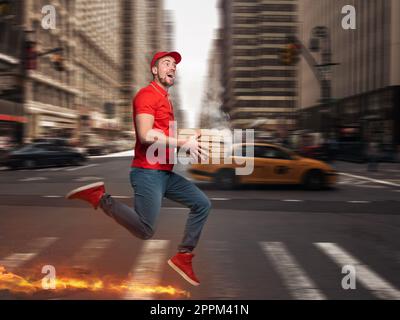 Messenger en uniforme rouge fonctionne à pied très rapidement pour livrer rapidement des pizzas chaudes juste cuites Banque D'Images