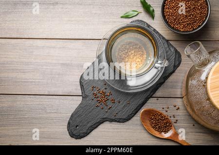 Tasse de thé de sarrasin aromatique fraîchement préparé et granulés sur table en bois, plat. Espace pour le texte Banque D'Images