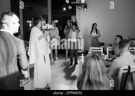 une mariée dans une robe blanche jette un bouquet de mariage Banque D'Images