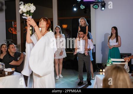 une mariée dans une robe blanche jette un bouquet de mariage Banque D'Images