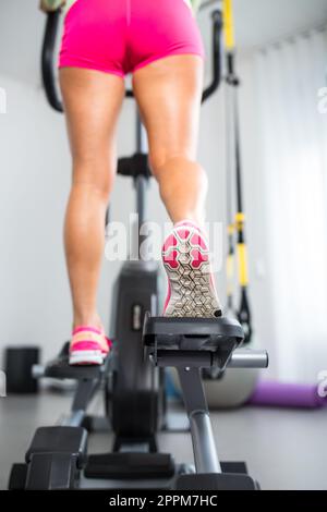 La jeune femme jambes musclées sur tapis roulant/pas-à-pas, gros plan Banque D'Images