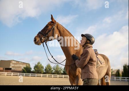 Femme pilote passant du temps avec son cheval préféré en plein air Banque D'Images