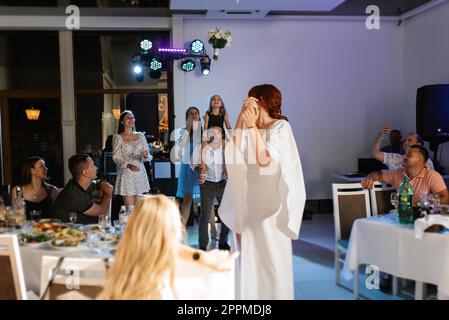 une mariée dans une robe blanche jette un bouquet de mariage Banque D'Images