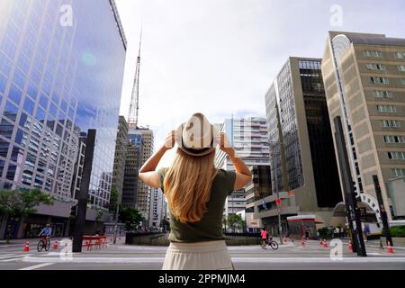 Belle fille arrive dans la grande ville de Sao Paulo. Jeune femme avec chapeau sur l'avenue Paulista à Sao Paulo, Brésil. Banque D'Images