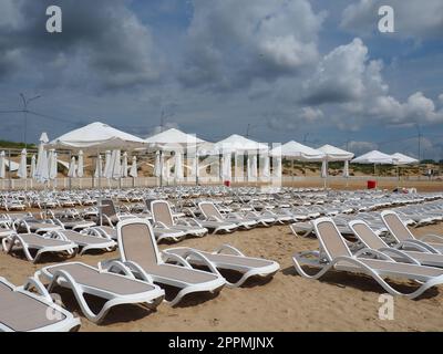 Anapa, Russie, le 15 août 2021 transats humides et parasols sur la plage de la mer pendant une forte pluie. Parasol roulé sur la plage contre le ciel nuageux sombre. Invasion d'un typhon, d'un cyclone ou d'une tempête Banque D'Images