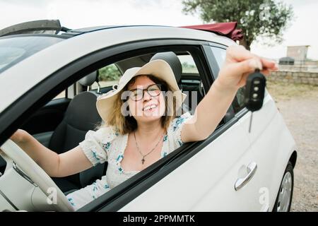 Voiture conducteur femme souriant montrant de nouvelles clés de voiture et de voiture. Une femme en voiture a loué cabrio pendant les vacances d'été Banque D'Images