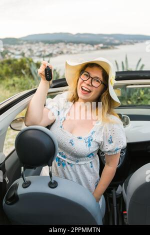 Voiture conducteur femme souriant montrant de nouvelles clés de voiture et de voiture. Une femme en voiture a loué cabrio pendant les vacances d'été Banque D'Images