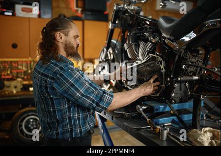 Homme mécanicien de réparer le moteur de moto travaillant dans un atelier de garage Banque D'Images