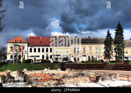 Sremska Mitrovica, Serbie, 16 mars 2023 place historique Zitni trg. Anciens bâtiments multicolores et fouilles de l'époque romaine. Patrimoine culturel. Ciel spectaculaire. Fouilles de chambres romaines. Banque D'Images