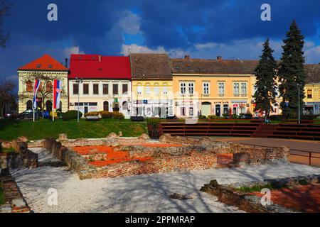 Sremska Mitrovica, Serbie, 16 mars 2023 place historique Zitni trg. Anciens bâtiments multicolores et fouilles de l'époque romaine. Patrimoine culturel. Ciel spectaculaire. Fouilles de chambres romaines. Banque D'Images