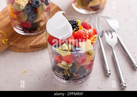 Salade de fruits aux baies, zeste d'agrumes, vinaigrette à la menthe et au miel servie dans un verre avec une cuillerée de crème fouettée Banque D'Images
