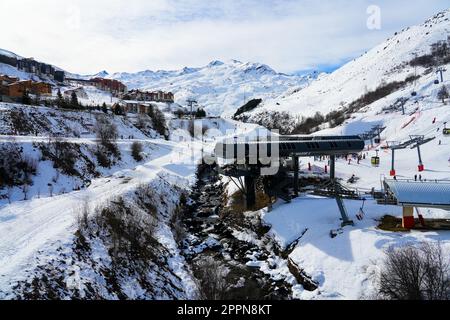 Ruisseau de glace fondue dans une vallée enneigée des Alpes françaises près de la station de ski des Ménuires en hiver Banque D'Images