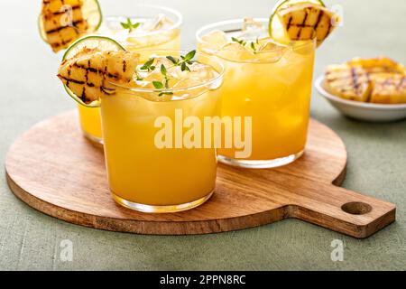 margarita à l'ananas grillé garni de quartiers de citron vert et de thym Banque D'Images