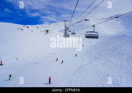 Piste de ski enneigée dans les montagnes au-dessus de la station de ski des Ménuires dans les Alpes françaises, vue depuis un télésiège Banque D'Images