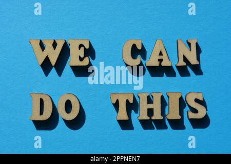 Nous pouvons le faire, des mots en lettres de l'alphabet en bois isolées sur fond bleu Banque D'Images