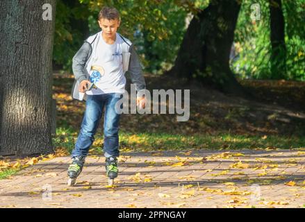 Minsk Mazowiecki, Pologne - 14 octobre 2019: Même patinage sur roulettes le garçon tient un iPhone dans ses mains. Le trouble de la dépendance sur Internet se forme rapidement Banque D'Images