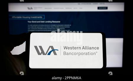 Personne tenant un smartphone avec le logo de la société américaine Western Alliance Bancorporation à l'écran devant le site Web. Mise au point sur l'affichage du téléphone. Banque D'Images