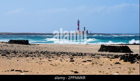 Plage le long de la côte Atlantique avec vue sur le phare d'El Toston sur la côte nord de Fuerteventura dans les îles Canaries, en Espagne Banque D'Images