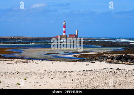 Lagon peu profond le long de la côte atlantique avec vue sur le phare d'El Toston sur la côte nord de Fuerteventura dans les îles Canaries, en Espagne Banque D'Images