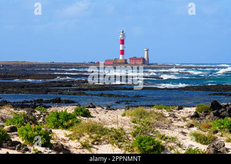 Plage le long de la côte Atlantique avec vue sur le phare d'El Toston sur la côte nord de Fuerteventura dans les îles Canaries, en Espagne Banque D'Images