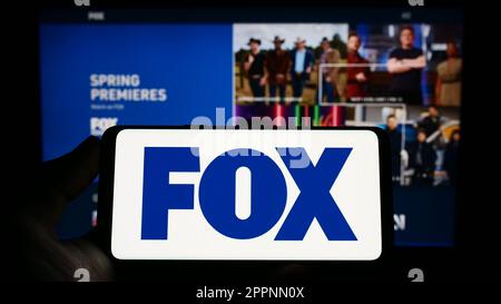 Personne tenant un smartphone avec le logo de la société américaine de médias de masse Fox Corporation à l'écran devant le site Web. Mise au point sur l'affichage du téléphone. Banque D'Images
