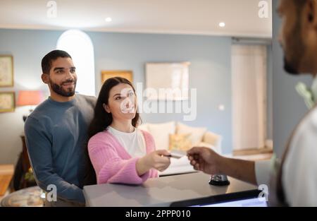 Un couple s'est placé à l'hôtel et a donné sa carte de crédit à la réceptionniste à l'intérieur Banque D'Images