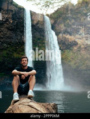 Homme debout devant la cascade de Wailua sur Kauai, Hawaï. Photo de haute qualité. Situé dans le parc national de Wailua River. Voyage à Hawaï Banque D'Images