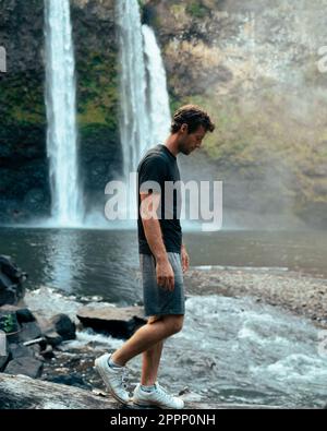 Homme debout devant la cascade de Wailua sur Kauai, Hawaï. Photo de haute qualité. Situé dans le parc national de Wailua River. Voyage à Hawaï Banque D'Images