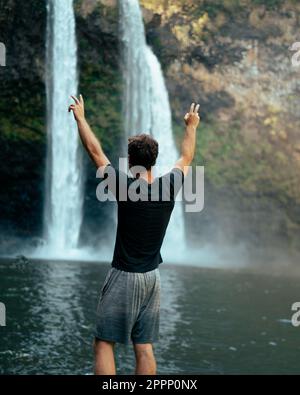 Homme debout devant la cascade de Wailua sur Kauai, Hawaï. Photo de haute qualité. Situé dans le parc national de Wailua River. Voyage à Hawaï Banque D'Images